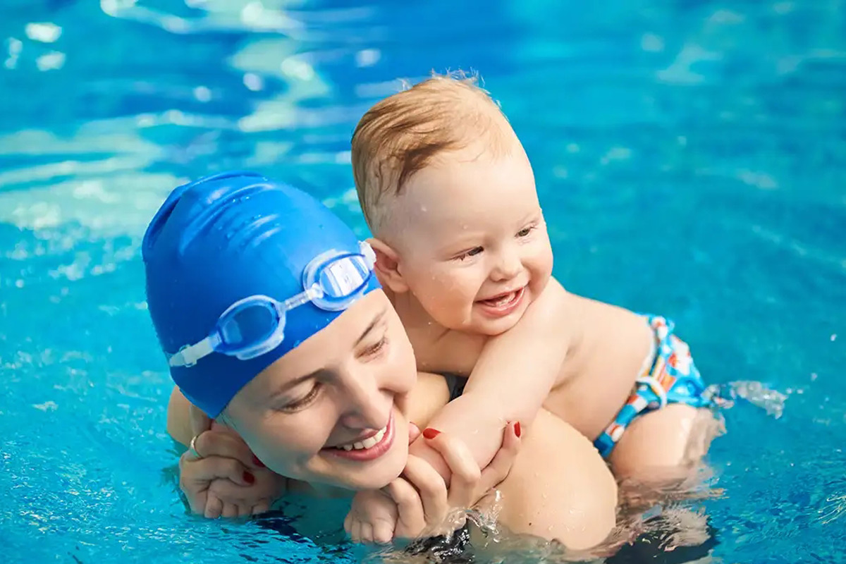 Acquaticita neonatale - bimbo piccolo che nuota in piscina con la mamma