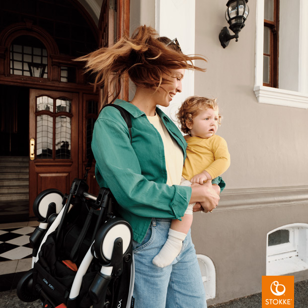 Stokke Yoyo 3 - Mamma che trasporta Yoyo 3 a tracolla tenendo il bimbo in braccio