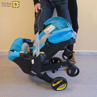 Simple Parenting Doona Infant Car Seat - Fase di apertura - mossa 2b - Sollevare il seggiolino verso l'alto tenendolo parallelo al pavimento, e permettere alle ruote di scendere