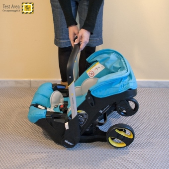 Simple Parenting Doona Infant Car Seat - Fase di chiusura - mossa 1d - Tenendo sempre il seggiolino dal maiglione, portarlo verso il pavimento per permettere la chiusura completa delle ruote